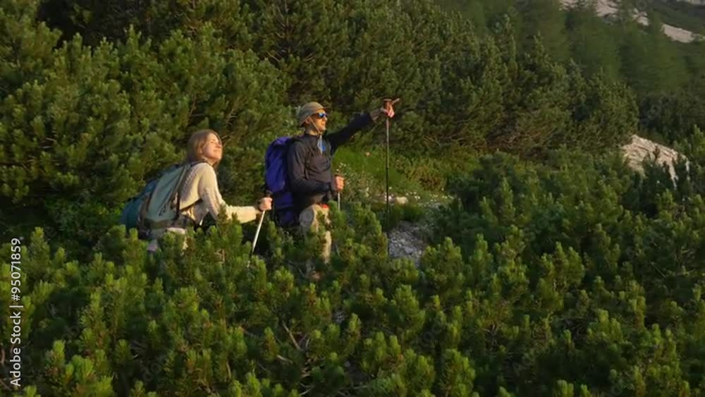 AERIAL: Couple admiring the view while hiking the mountain AERIAL: Couple admiring the view while hiking the mountain