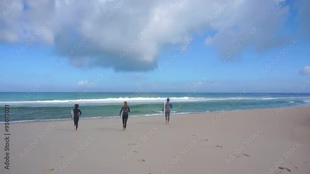 AERIAL: Surfers running into the ocean with surfboards AERIAL: Surfers running into the ocean with surfboards