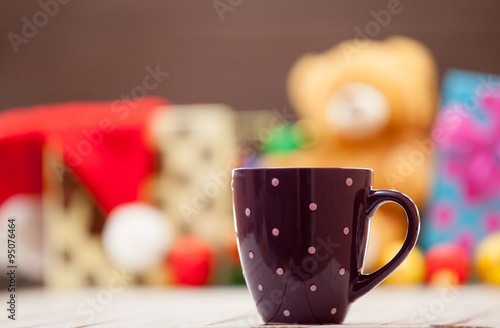 Cup with christmas gifts on background
