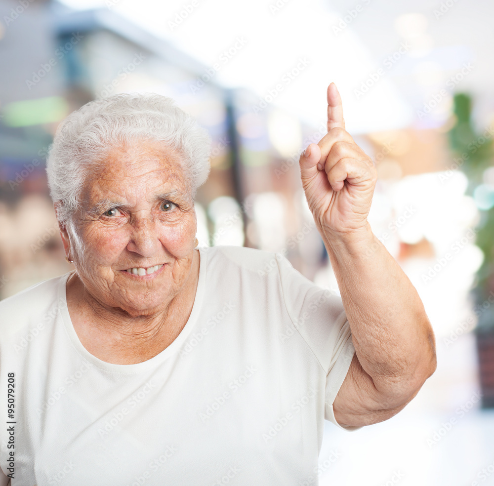 portrait of adorable old woman pointing up with her finger portrait of adorable old woman pointing up with her finger