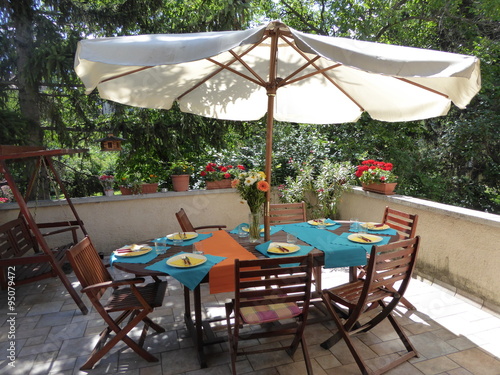 Set table below a sunshade in a beautiful green garden