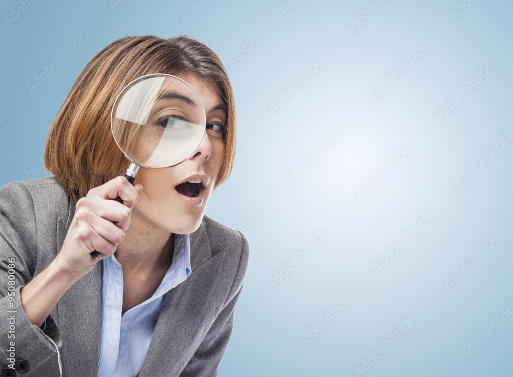 Wall Mural portrait of an executive young woman looking through a magnifying glass