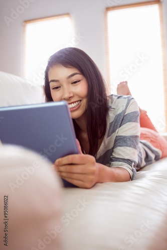 Smiling asian woman on couch using tablet © WavebreakMediaMicro