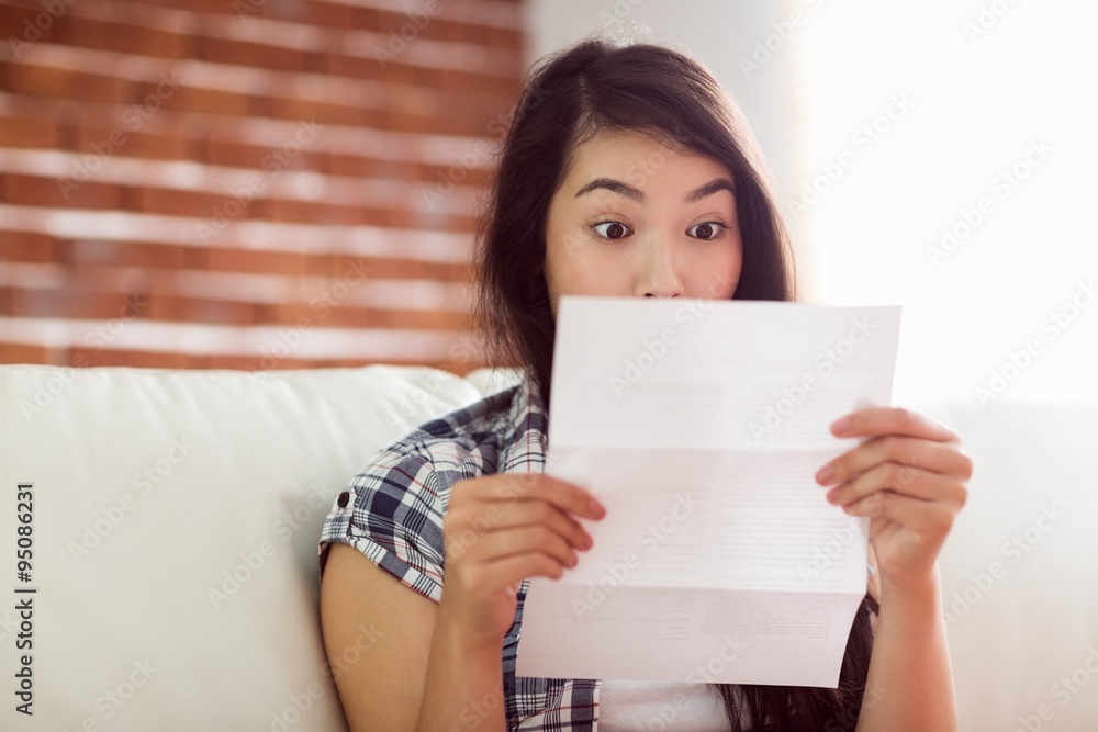 Asian woman on the couch reading letter