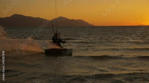 SLOW MOTION: Kitesurfer splashing the water at sunset
