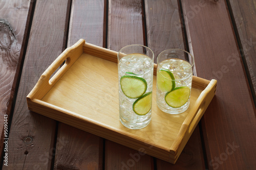Obraz na płótnie Two drinks on wooden tray with ice and condensation on glass w salonie