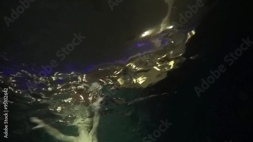 Underwater view of swimming girl in dark  photo