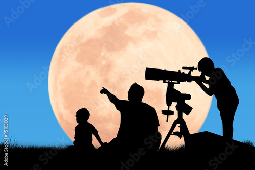silhouette of little boy looking through a telescope at the full