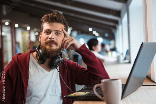 Photos Young confident guy working in office using headset and laptop