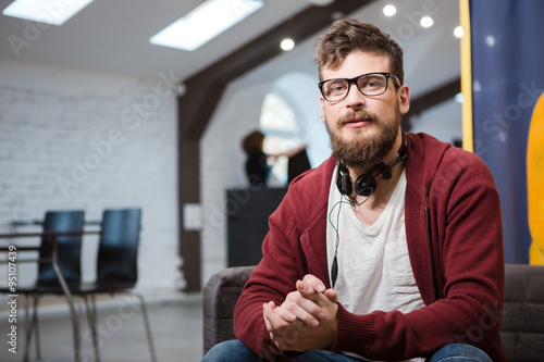 Hipster in glasses with beard sitting on sofa