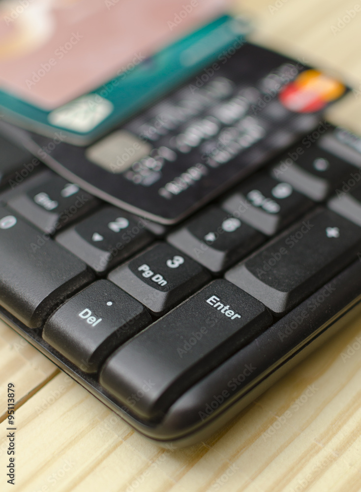 close up of a computer keyboard with credit card on top. focus on enter button