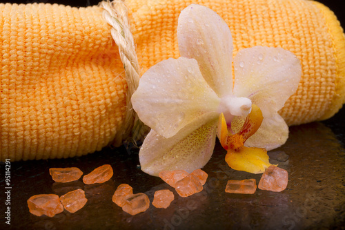 flower yellow-orange orchids and orange towel on glossy black ba