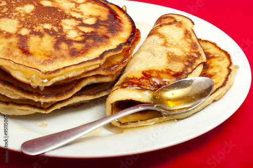 delicious pancakes with honey sauce on red background