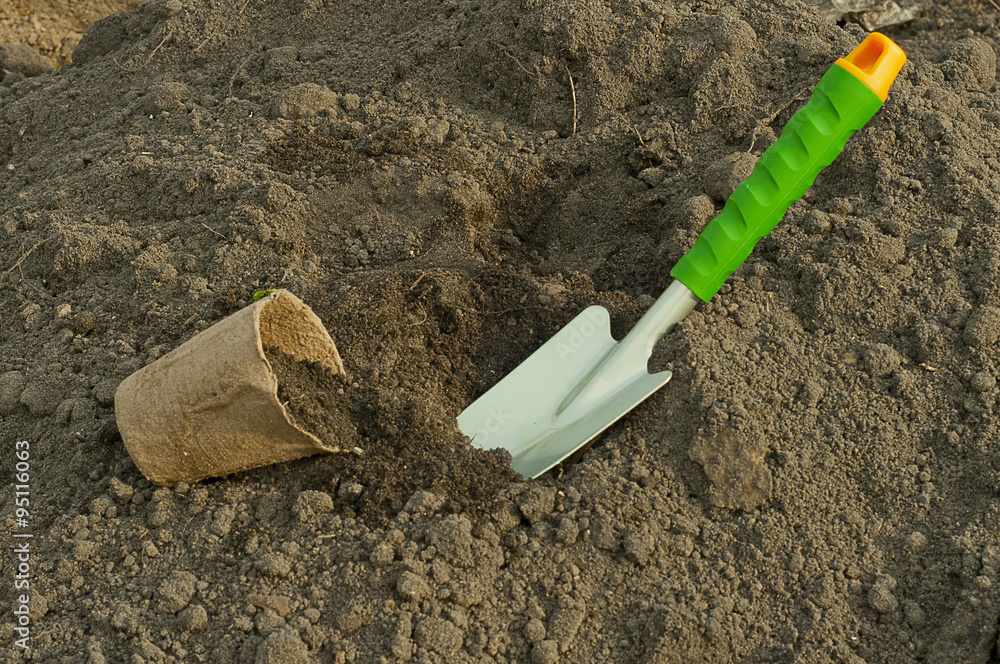 green shovel and peat pot for seedlings in the ground green shovel and peat pot for seedlings in the ground