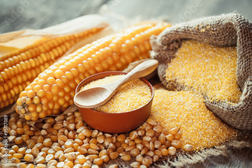 Photos Corn groats and dry seeds, corncobs on wooden rustic table.