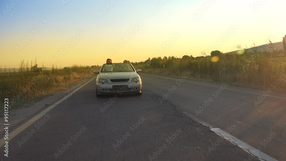 Couple driving convertible, cabriolet car with sunset Couple driving convertible, cabriolet car with sunset