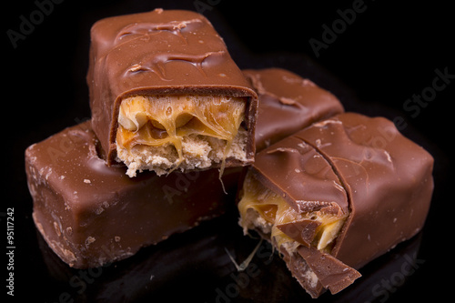 slices of Snickers bars on a black background macro photo
