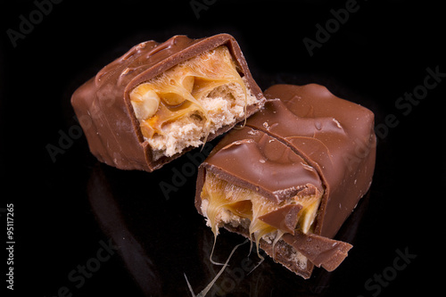 two slices of Snickers bars on a black background macro