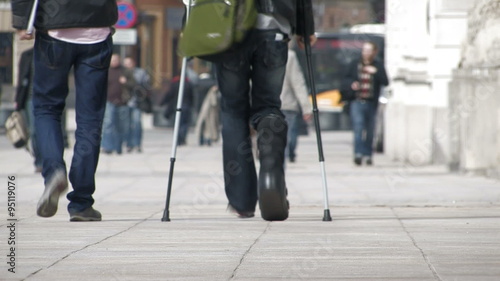 Young man on crutches walking in the crowd