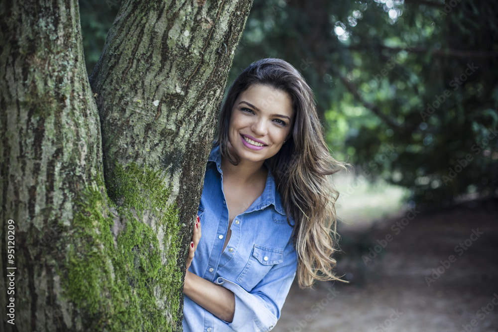 Girl hides behind a tree trunk Girl hides behind a tree trunk