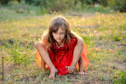 A Little Girl in a Red Dress Posing Outdoors