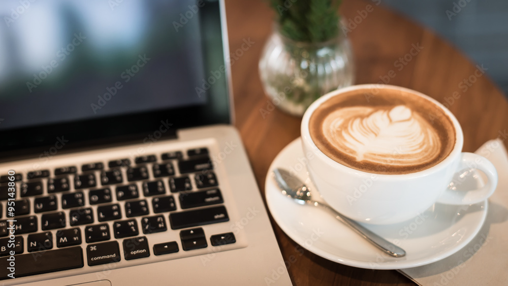 Hot art Latte Coffee in a cup and laptop on wooden table in Coff Hot art Latte Coffee in a cup and laptop on wooden table in Coff