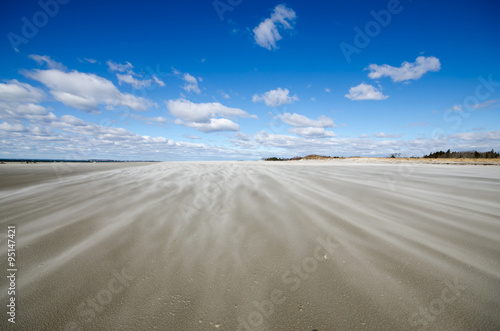 Blowing Sand across Empty Deserted Beach with Clear Sunny Blue Sky