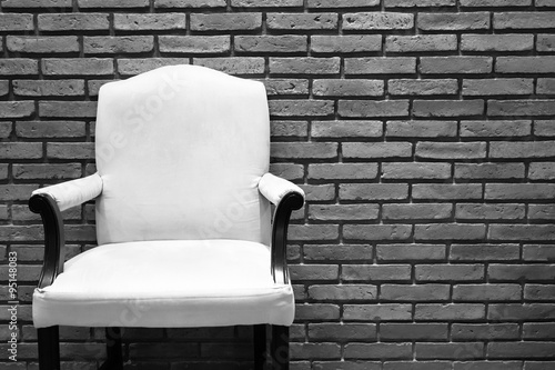 White chair in front of grey brick wall.