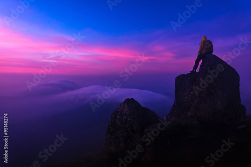 traveler standing on the rock with Sunrise scene and mist at mou