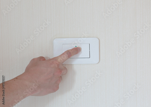 man hand with finger on light switch, about to turn on the light