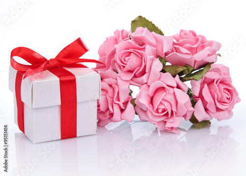 pink flowers and gift box with red ribbon and bow on a white ba