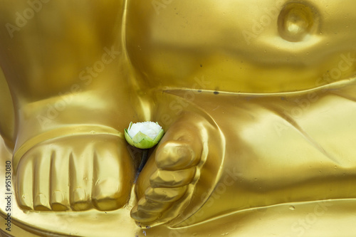 Lotus on feet of golden buddha statue at Wat Arun temple in Thailand photo