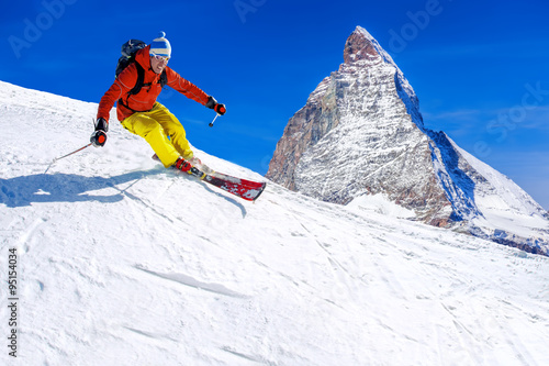 Skier skiing downhill against Matterhorn peak in Switzerland