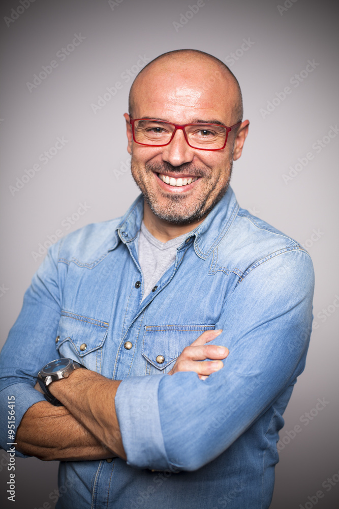 Hombre calvo de mediana edad con gafas rojas sonriendo Photos | Adobe Stock