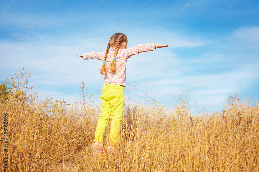 Little girl in bright clothes standing against the sky Little girl in bright clothes standing against the sky
