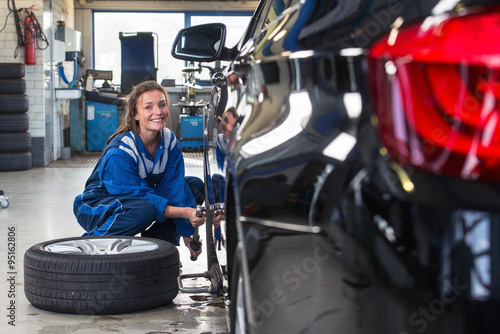 Female service mechanic changing the front tire of a car