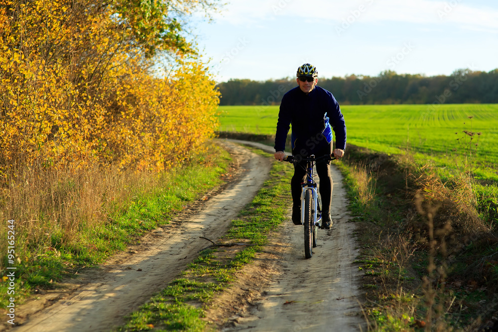 young adult cyclist riding mountain bike in the countryside young adult cyclist riding mountain bike in the countryside
