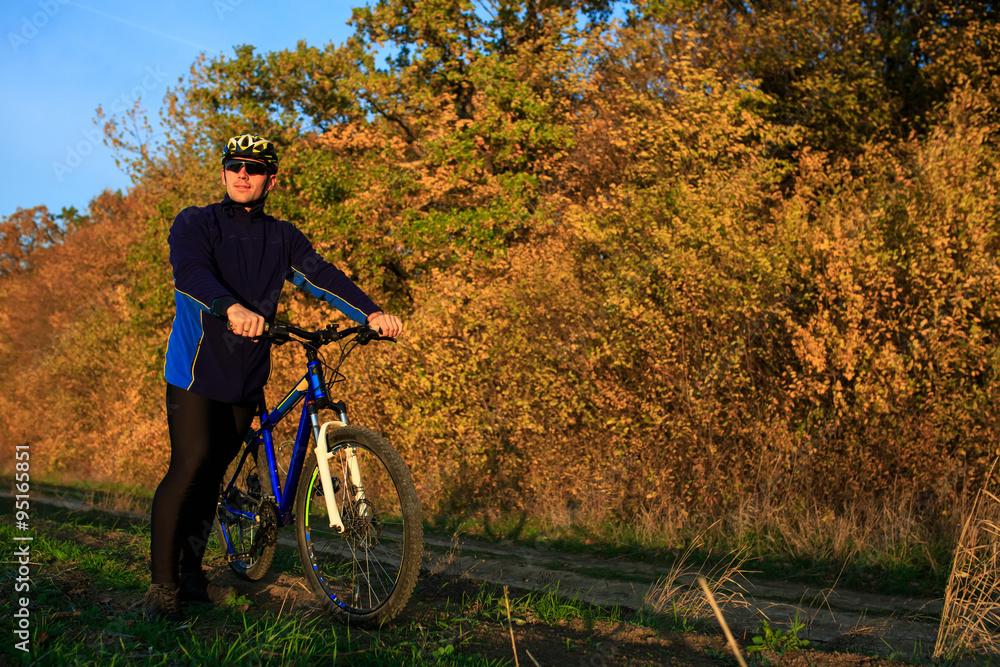 Obraz premium young adult cyclist riding mountain bike in the countryside