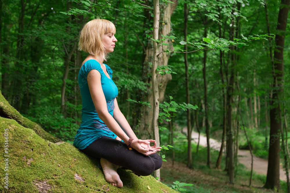 Young woman in seated meditation yoga pose in forest. Young woman in seated meditation yoga pose in forest.