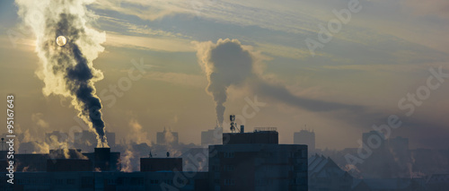 Environmental pollution. It is very cold in the morning sunrise in city, smoking chimneys. photo