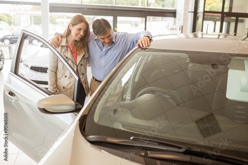 Murais de parede Smiling couple leaning on car