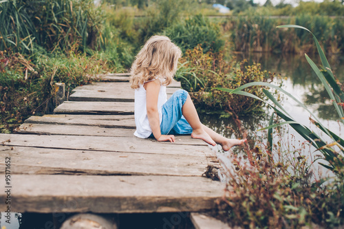 little girl sitting on a wooden pier © jul14ka