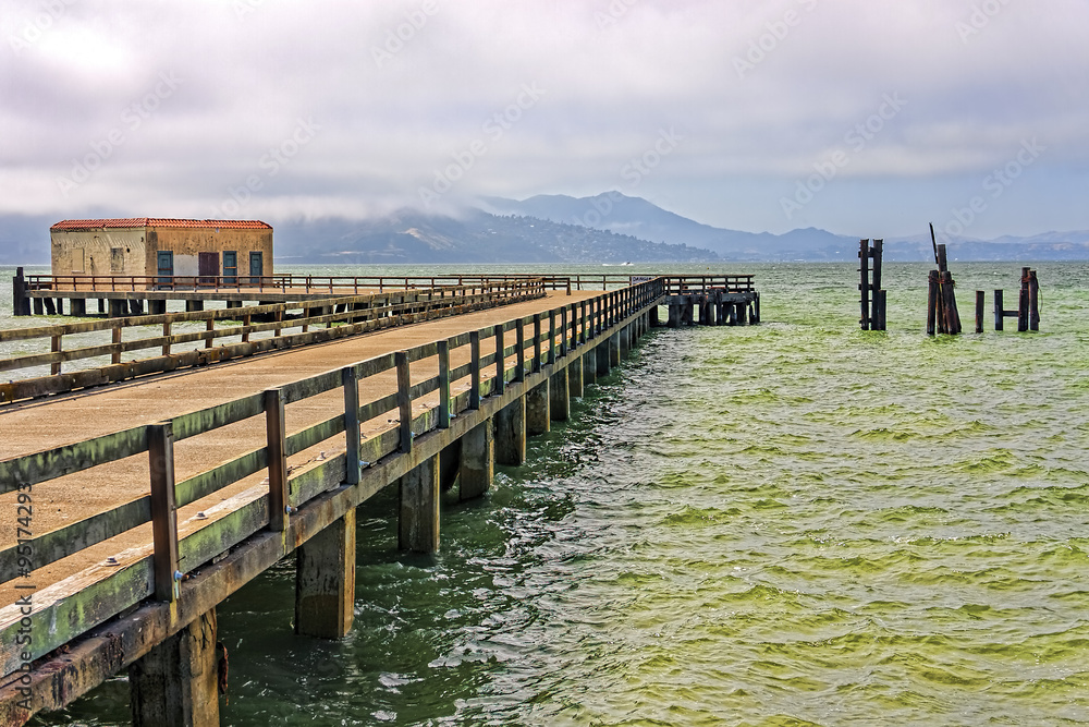 Wooden pier out across San Francisco Bay on a cloudy day.