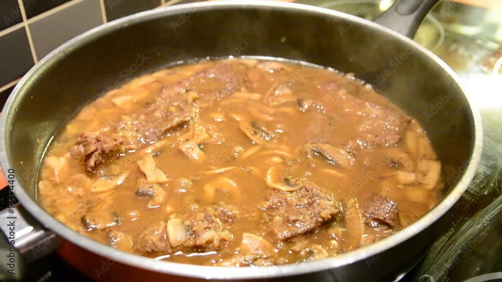 Cooking striploin beef meat with sauce and mushrooms in the pan closeup. Cooking striploin beef meat with sauce and mushrooms in the pan closeup.