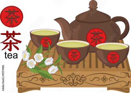Kettle, small cups of green tea on a wooden table and flowers of tea.