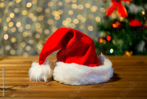 close up of santa hat on wooden table over lights