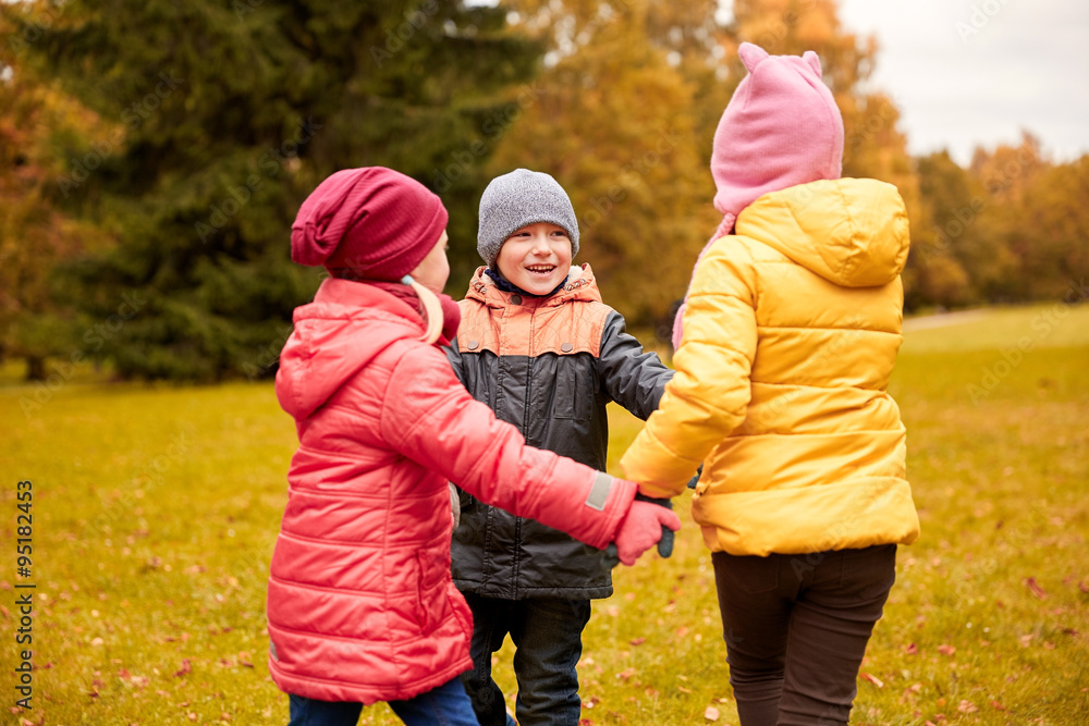 children holding hands and playing in autumn park children holding hands and playing in autumn park