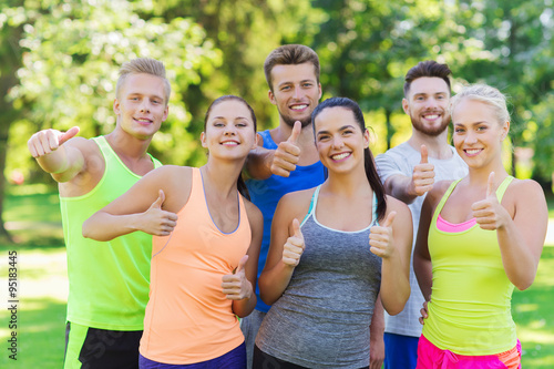 group of happy sporty friends showing thumbs up