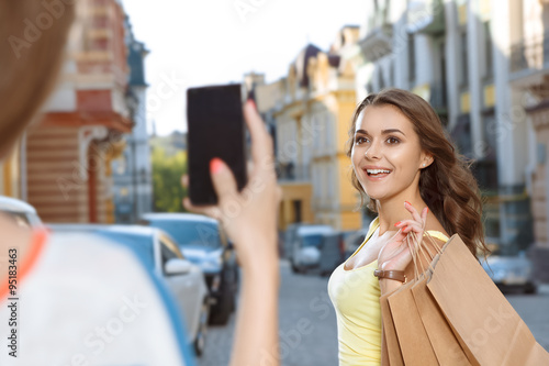 Two young girls taking pictures while shopping