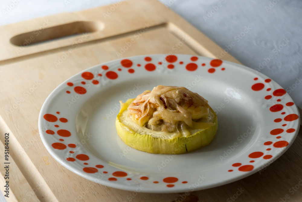 Zucchini stuffed with meat on plate and wood kitchen table. 